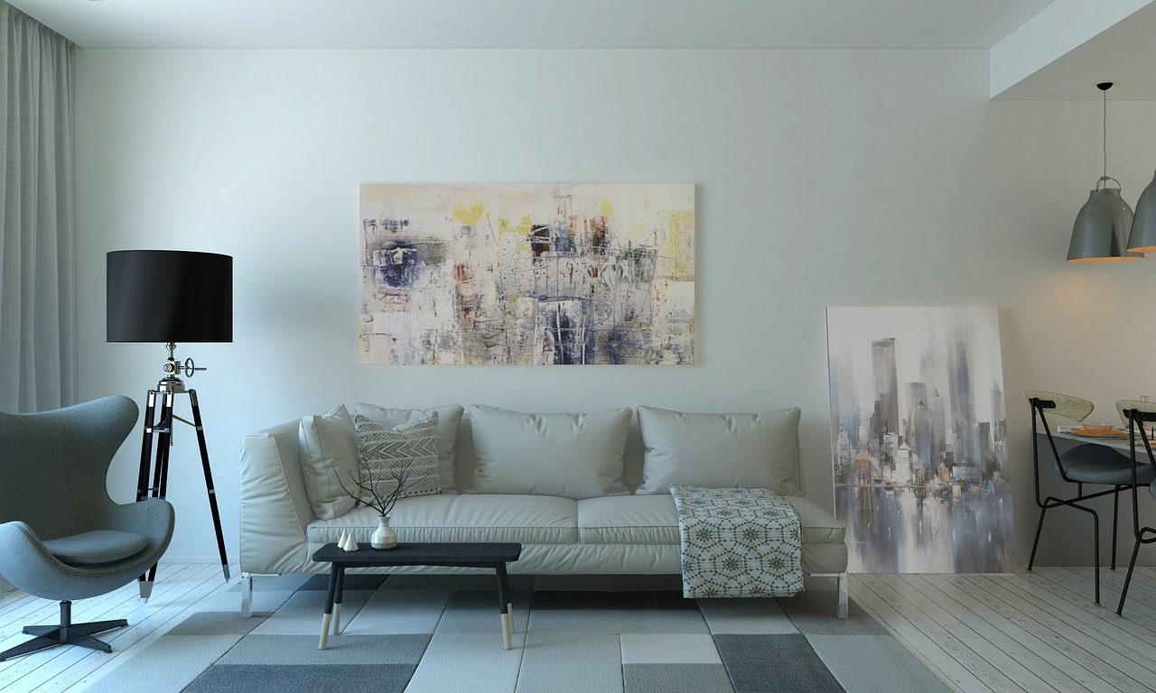 Salon moderne avec canapé clair, lampadaire noir et tableau abstrait au mur, illustrant un intérieur propre et bien entretenu